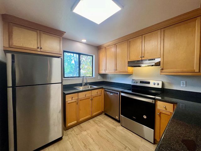 a kitchen with stainless steel appliances granite countertop a refrigerator a sink dishwasher a stove top oven and cabinets