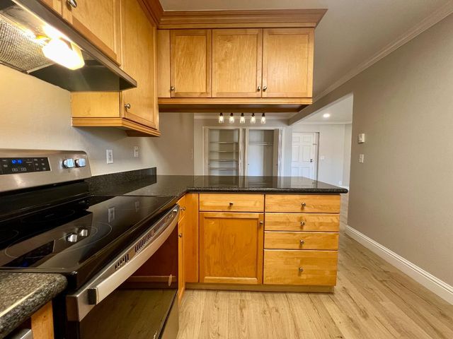 a kitchen with granite countertop cabinets and wooden floor