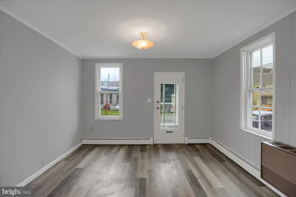 an empty room with wooden floor and windows