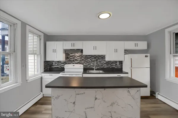 a kitchen with a stove a refrigerator and white cabinets