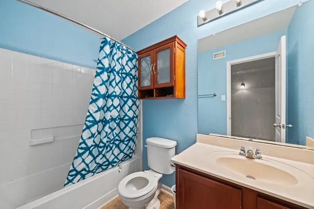 a bathroom with a sink a toilet and shower curtain
