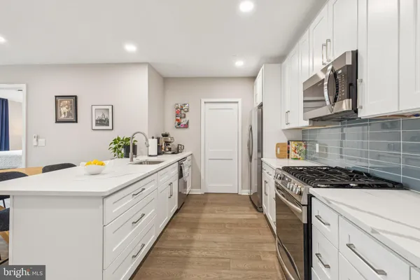 a kitchen with stainless steel appliances a stove a sink a microwave a refrigerator and white cabinets