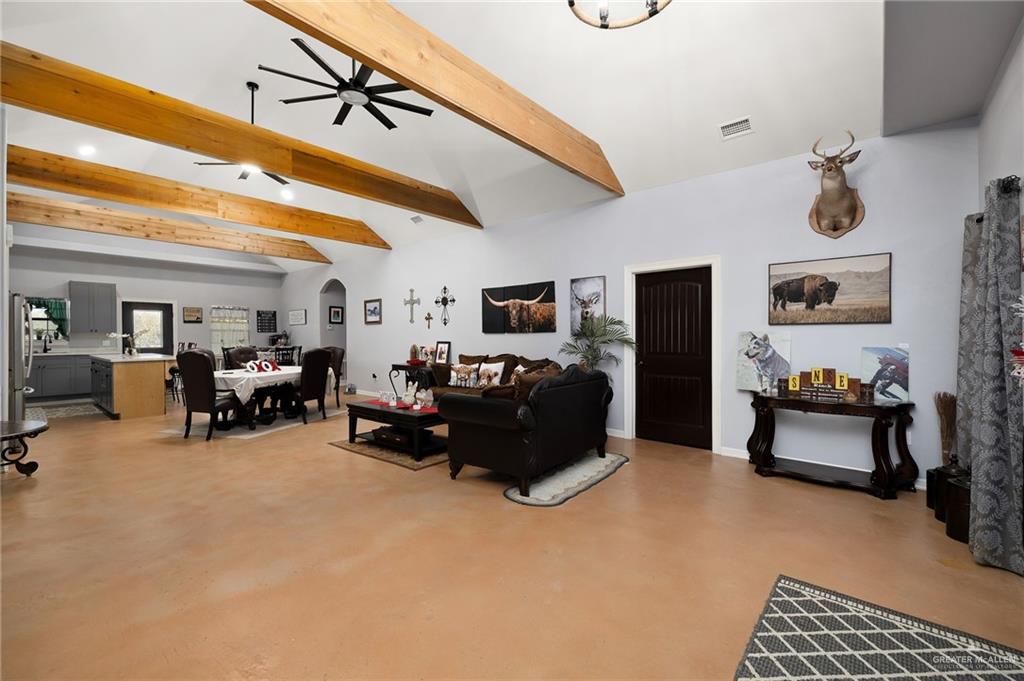 2991 North Us Highway Roma, TX 78584 - Photo 5 of 28 Living room featuring concrete floors, beam ceiling, arched walkways, ceiling fan, and high vaulted ceiling