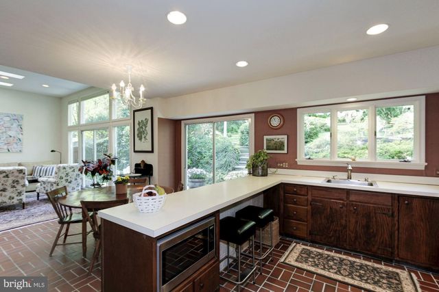 a kitchen with a stove a sink dishwasher and a dining table with garden view