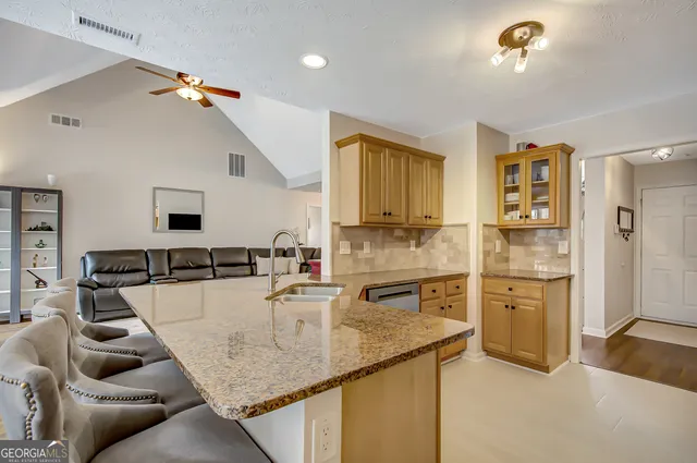 a kitchen with stainless steel appliances granite countertop a sink and dishwasher a refrigerator with wooden floor
