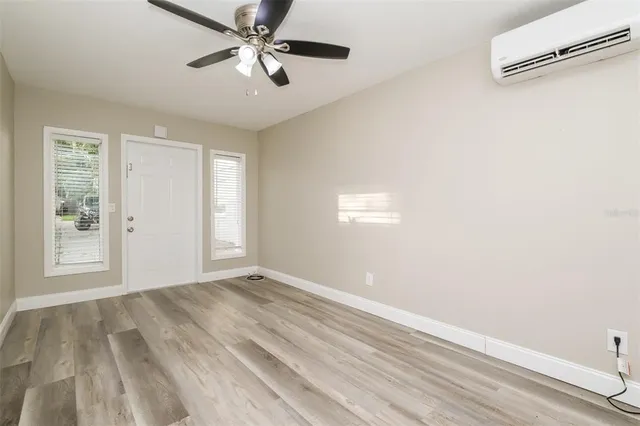 a view of an empty room with window and chandelier fan