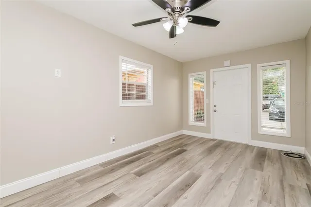 a view of an empty room with a window and wooden floor