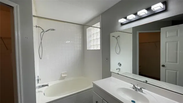 a bathroom with a tub shower sink and mirror