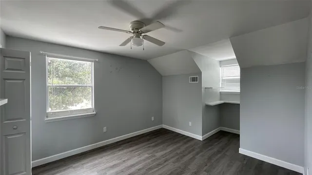 a view of an empty room with a window and wooden floor