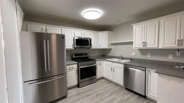 a kitchen with cabinets stainless steel appliances and wooden floor