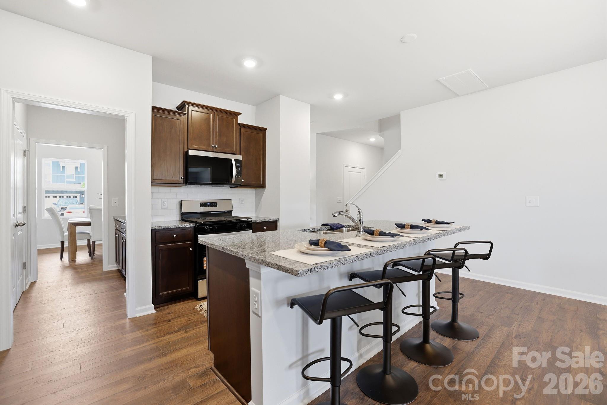 470 Brick House Road York, SC 29745 - Photo 15 of 39 a kitchen with stainless steel appliances granite countertop a stove a refrigerator a microwave a sink a dining table and chairs with wooden floor