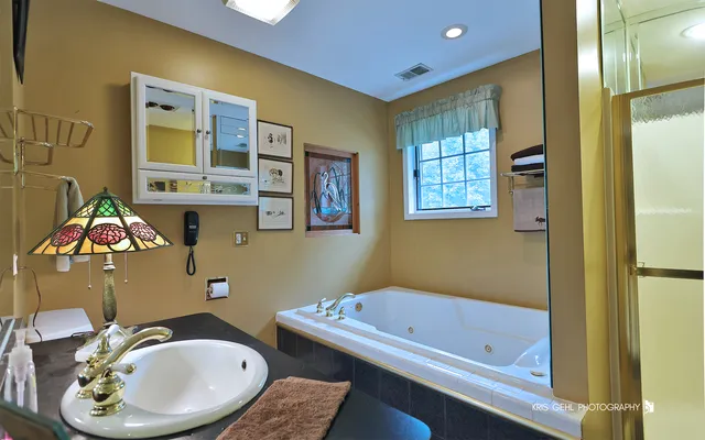 a bedroom with a bed a chandelier with dresser and mirror