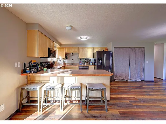 a kitchen with a refrigerator and wooden floor