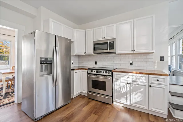 a kitchen with white cabinets stainless steel appliances and wooden floor