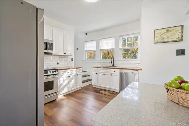 a kitchen with stainless steel appliances white cabinets a sink a stove a refrigerator and a granite counter tops with white cabinets