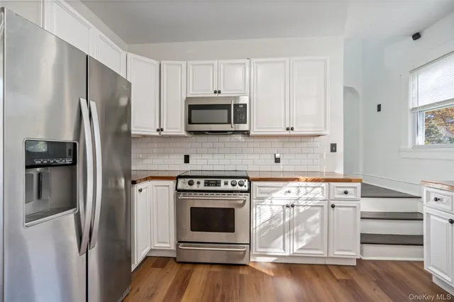 a kitchen with stainless steel appliances wooden floor sink and microwave