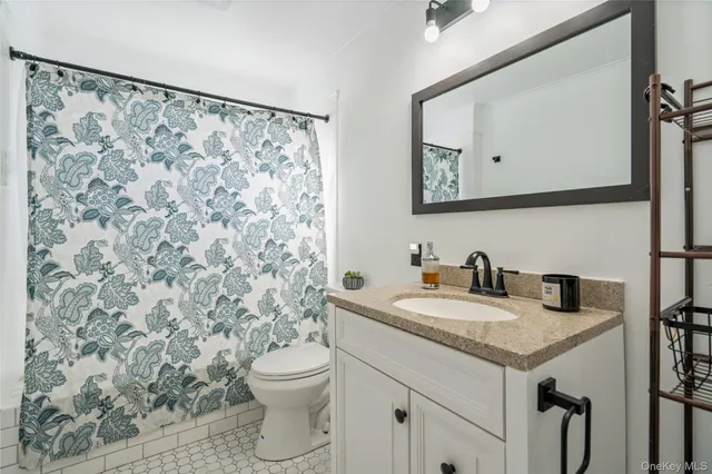 a bathroom with a granite countertop sink a toilet and a mirror