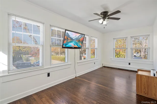 a view of an empty room with a window and wooden floor