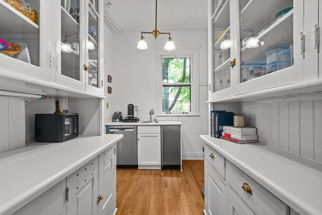 a kitchen with a sink dishwasher stove and white cabinets with wooden floor
