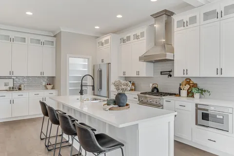a kitchen with stainless steel appliances a sink a stove a table and chairs