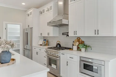 a kitchen with stainless steel appliances white cabinets and a stove top oven
