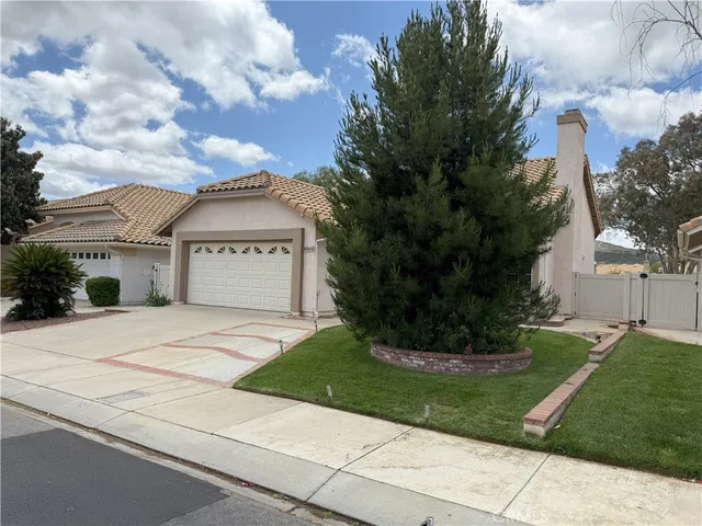a view of white house with a big yard and large tree