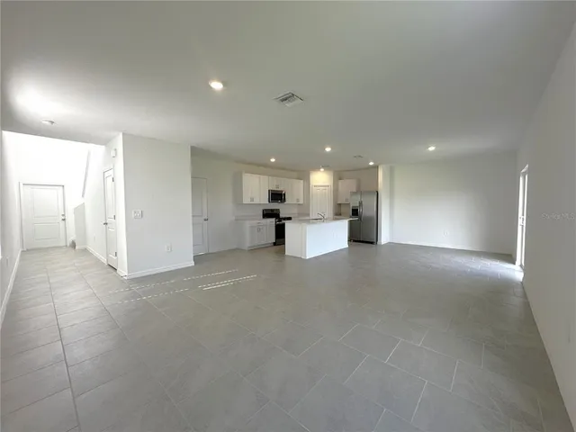 a view of a big room with windows and chandelier fan