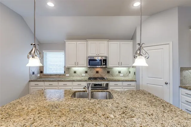 a kitchen with stainless steel appliances granite countertop a stove a sink and a refrigerator