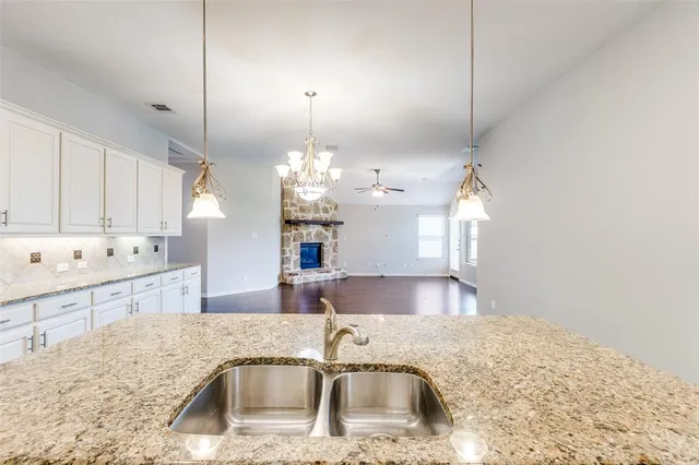 a kitchen with kitchen island a sink granite counter tops and a view of living room