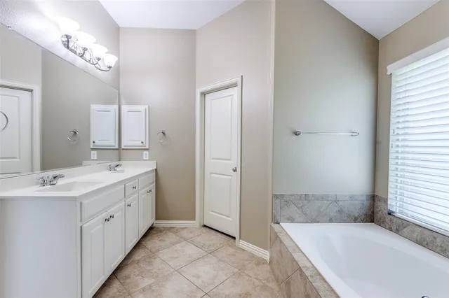 a spacious bathroom with a tub sink and mirror