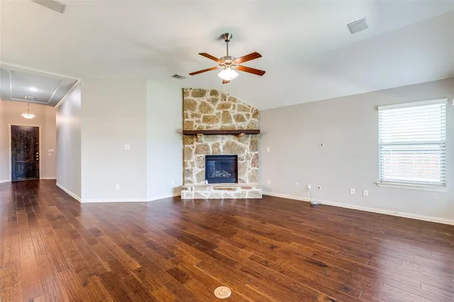 a view of an empty room with wooden floor fireplace and a window