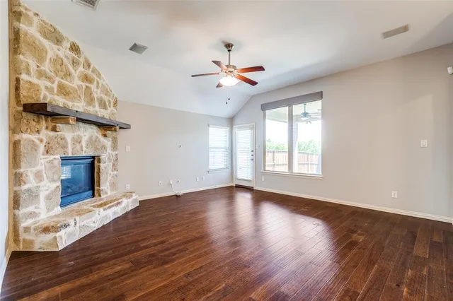 a view of an empty room with wooden floor fireplace and a window
