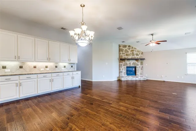 a view of an empty room with kitchen and stove top oven