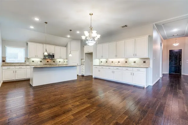 a kitchen with stainless steel appliances kitchen island a white cabinets and wooden floor