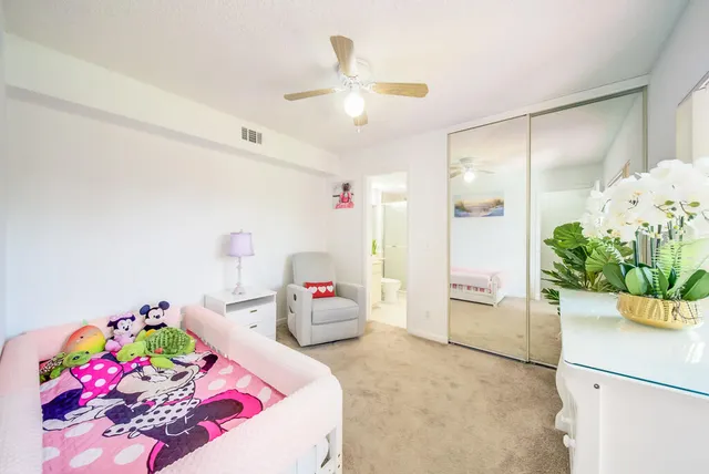 a bedroom with a bed potted plant on the dresser and floor