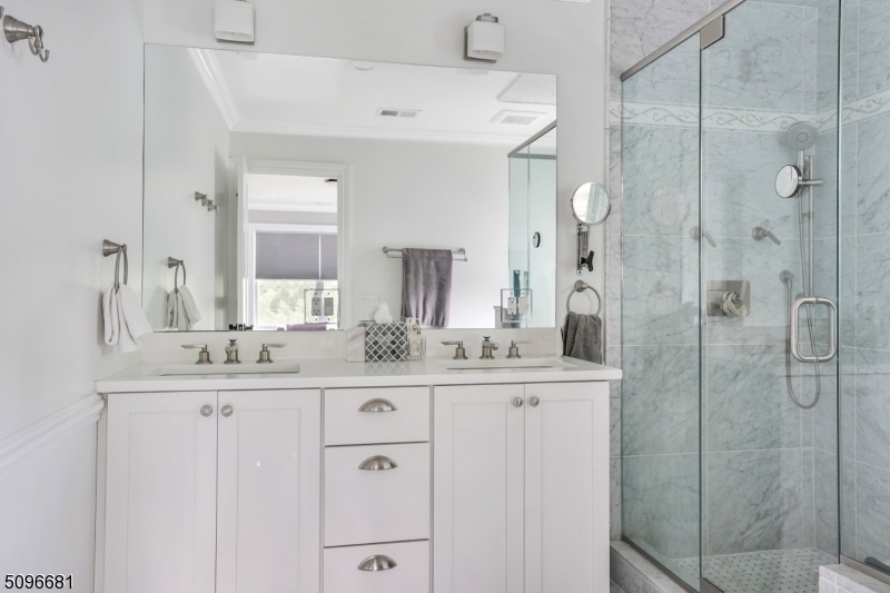 17 Spring Street Millburn, NJ 07041 - Photo 12 of 16 a bathroom with a granite countertop sink a mirror a vanity and a shower