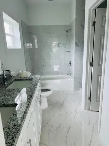 a bathroom with a granite countertop sink a toilet and bathtub