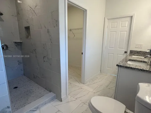 a bathroom with a granite countertop toilet a sink and a shower