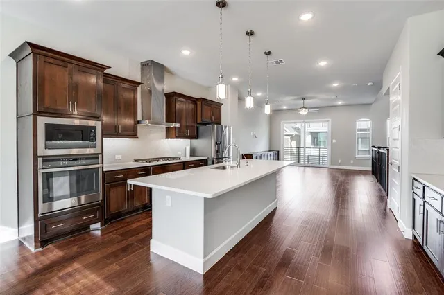 a kitchen with stainless steel appliances granite countertop a refrigerator a oven a stove and a wooden floors