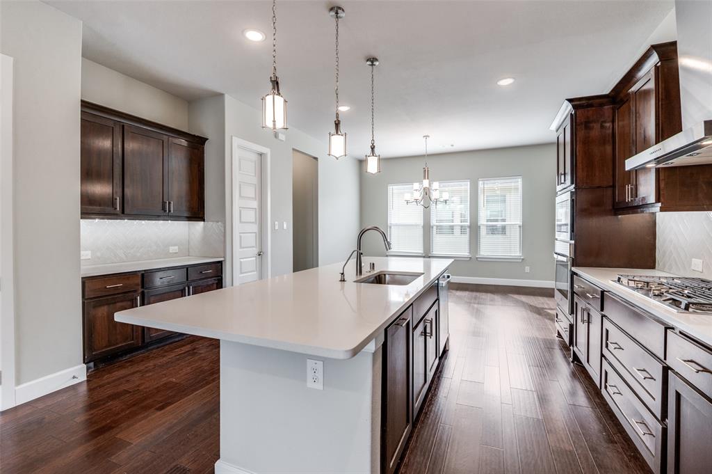 8233 Laflin Lane Dallas, TX 75231 - Photo 18 of 37 a large kitchen with kitchen island a stove a sink a refrigerator wooden floor and cabinets