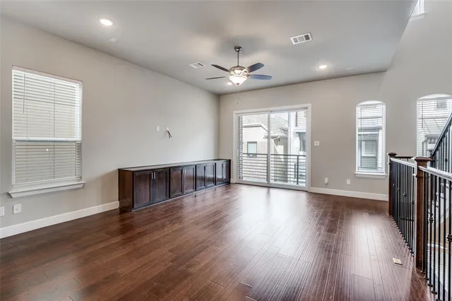 a view of an empty room with wooden floor and a kitchen