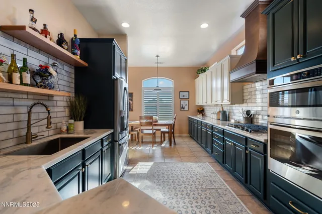 a large kitchen with stainless steel appliances granite countertop a stove a sink dishwasher a dining table and chairs with wooden floor