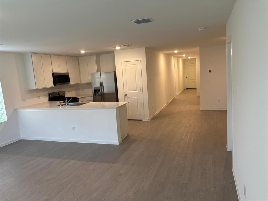 9204 Schram Road Fort Worth, TX 76179 - Photo 8 of 17 Open-concept living space featuring wood-finish flooring, a kitchen island with sink, white cabinetry, stainless steel appliances, and recessed lighting