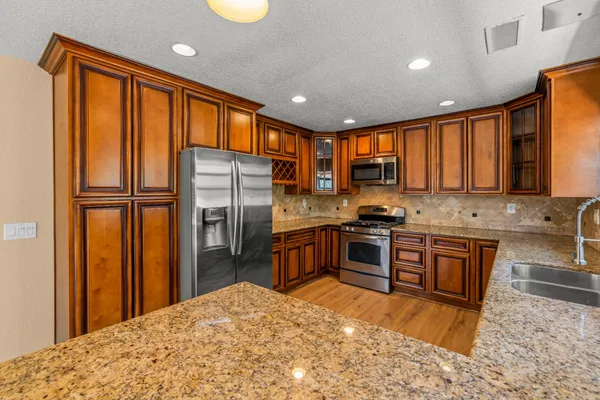 a kitchen with stainless steel appliances granite countertop a refrigerator stove top oven and sink