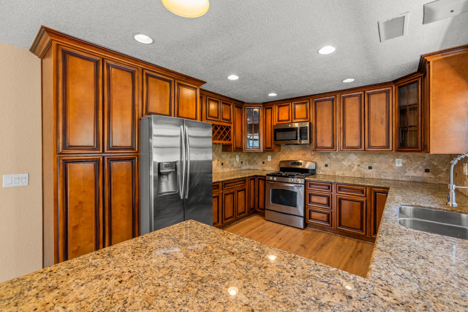 a kitchen with stainless steel appliances granite countertop a refrigerator stove top oven and sink