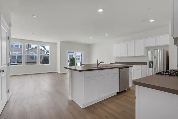 a kitchen with stainless steel appliances granite countertop a refrigerator a sink dishwasher a stove and white countertops with wooden floor