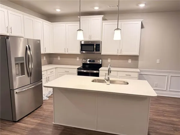 a kitchen with kitchen island a counter space a sink appliances and cabinets