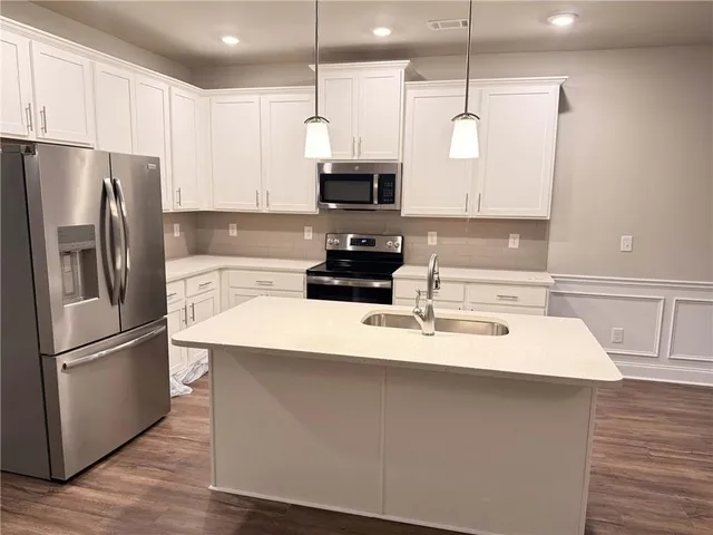 a kitchen with kitchen island a counter space a sink appliances and cabinets