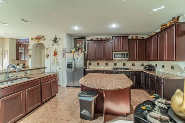 a kitchen with kitchen island granite countertop a sink stove and refrigerator