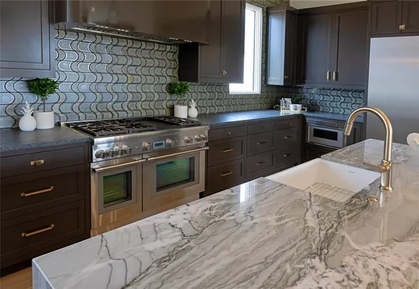 a kitchen with stainless steel appliances granite countertop a stove a sink and a microwave